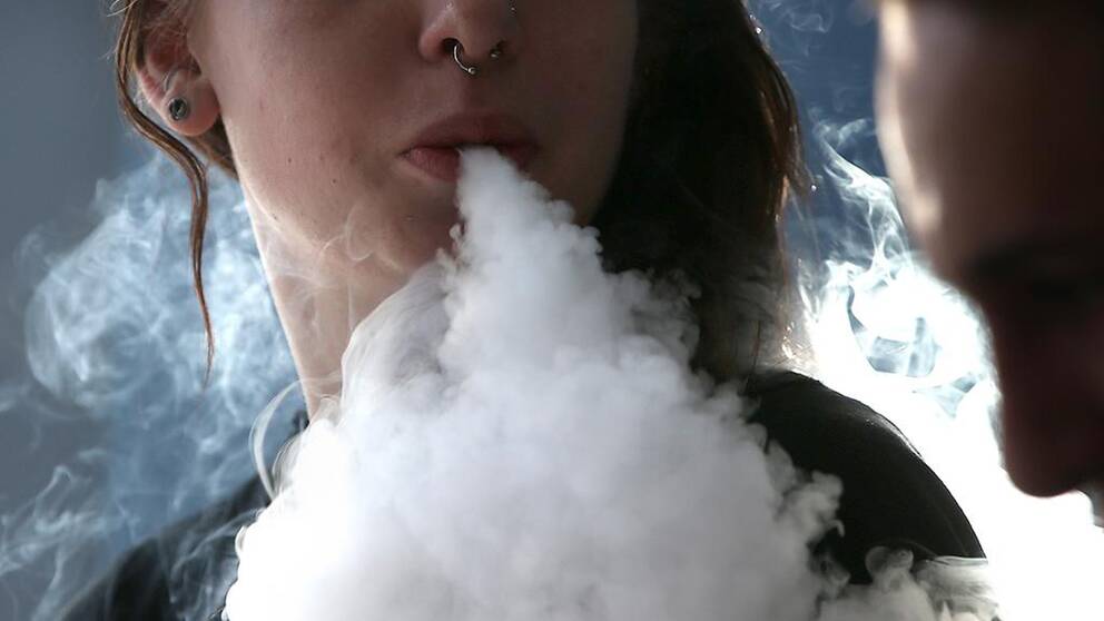 Ung kvinna röker e-cigarett.