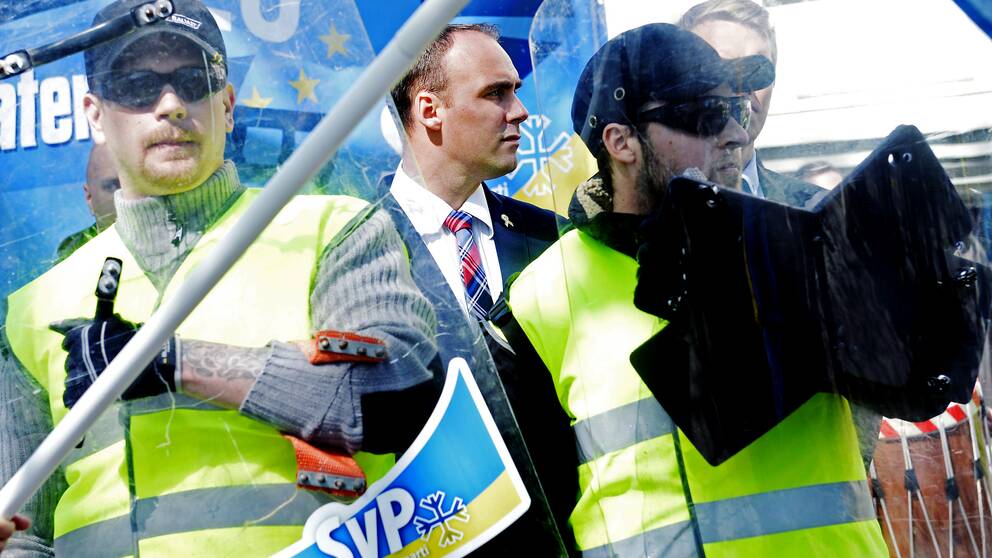 Partiledaren Stefan Jacobsson mellan sköldar i Svenskarnas Partis demonstrationståg i Jönköping första maj. 