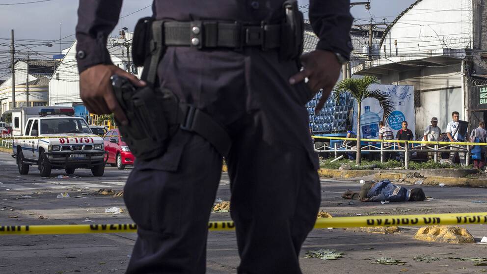 En polis bevakar en brottsplats efter ett mord i staden San Salvador.