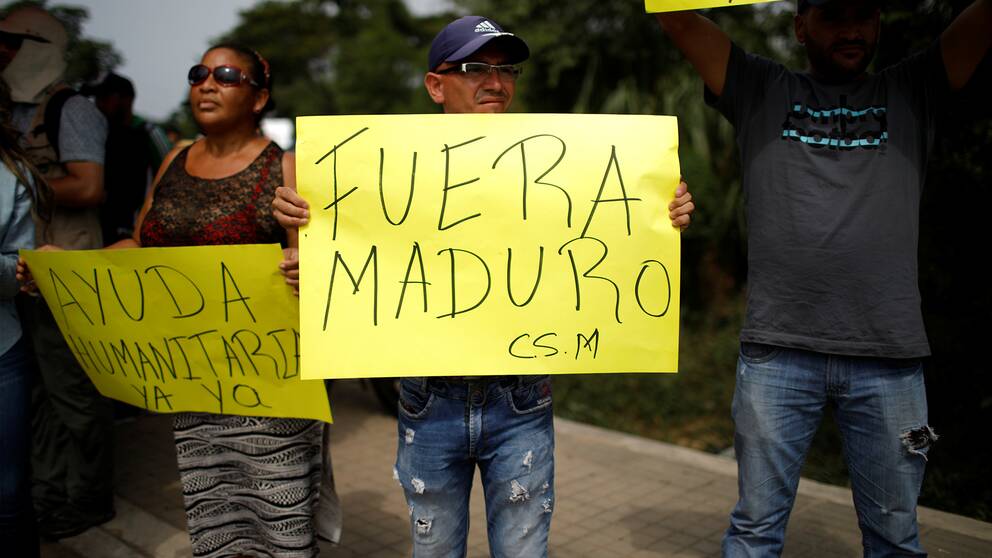 Venezolaner håller upp plakat i väntan på internationell humanitär hjälp.