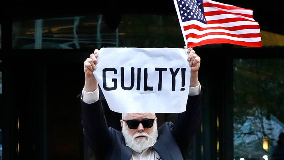 En demonstrant håller upp en skylt som det står ”Skyldig!” på och syftar på den före detta kampanjchefen Paul Manafort.