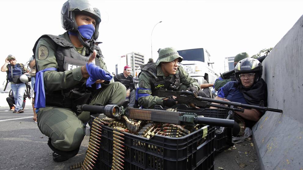 Soldater som gått över till oppositionsledaren Juan Guaido har knutit blå band på armen. Men trots att tungt beväpnade styrkor fanns bland demonstranterna i Caracas under onsdagen ska bara två personer har skadats av skottlossning, enligt CNN.