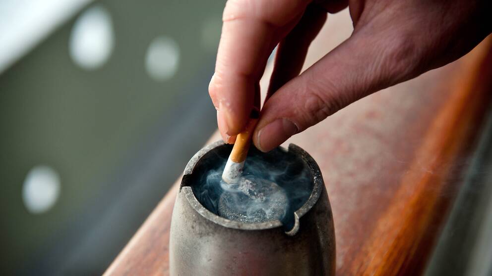 närbild hand som fimpar en cigarett i askkopp
