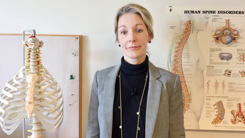 Sandra Schönbeck bredvid ett skelett och en plansch om ryggskador.