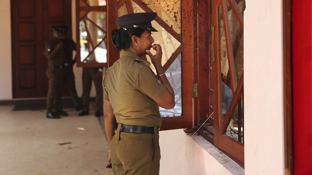 Poliskvinna i Sri Lanka tittar in i en av kyrkorna som attackerades i terrordåden.