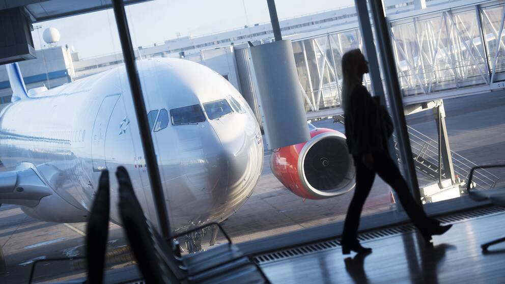 Flygplan och kvinna som går på en flygplats.