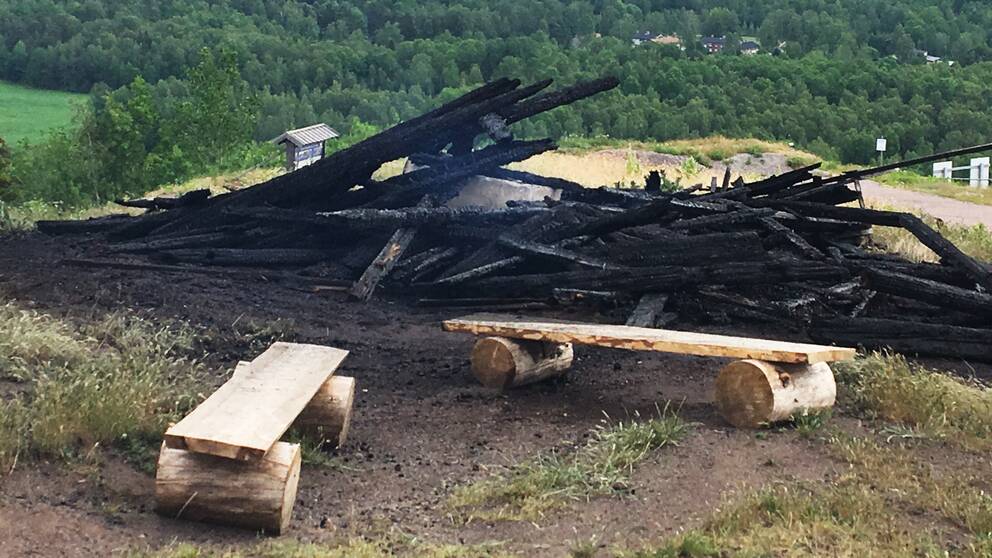 En hög svartbränt virke. Svag rök stiger från resterna efter konstverket ”Waaall”.