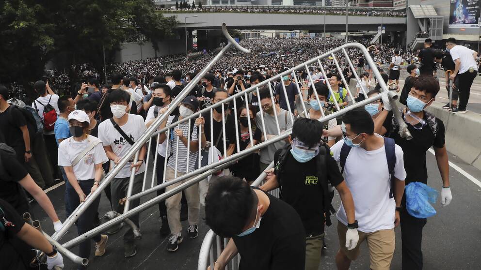 Demonstranter med ansiksmasker bär på metallstaket.