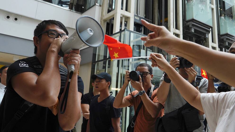 En demonstrant från proteströrelsen försöker göra sin röst hörd framför prokinesiska demonstranter i ett köpcentrum i Hongkong. Bild tagen fredag 13 september.