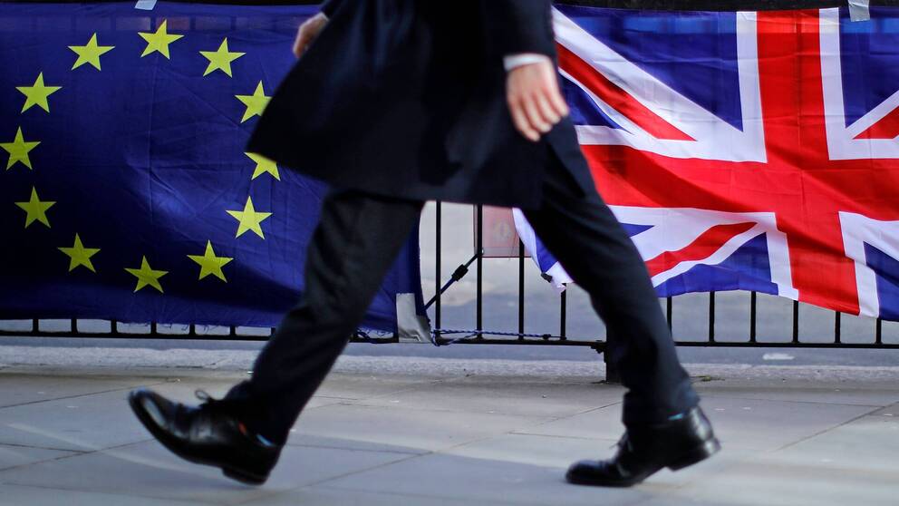 Bild på person som passerar den brittiska flaggan och EU-flaggan som kan symbolisera att Storbritannien snart kommer att lämna den Europeiska unionen (EU).