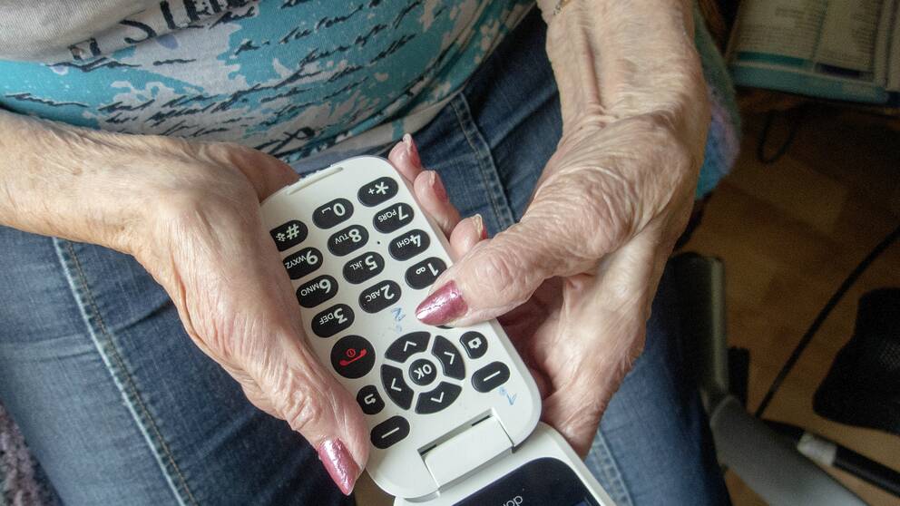 Kvinna håller i en knapptelefon.