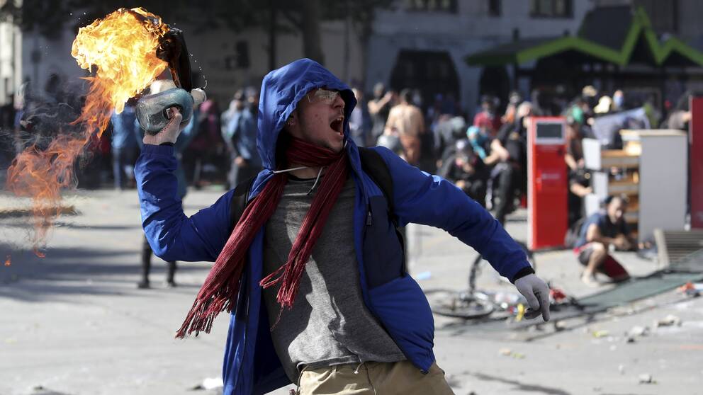 Demonstrant i Chile som kastar molotov-cocktail mot poliser när studenter och fackföreningar i landet demonstrerar mot regeringen.