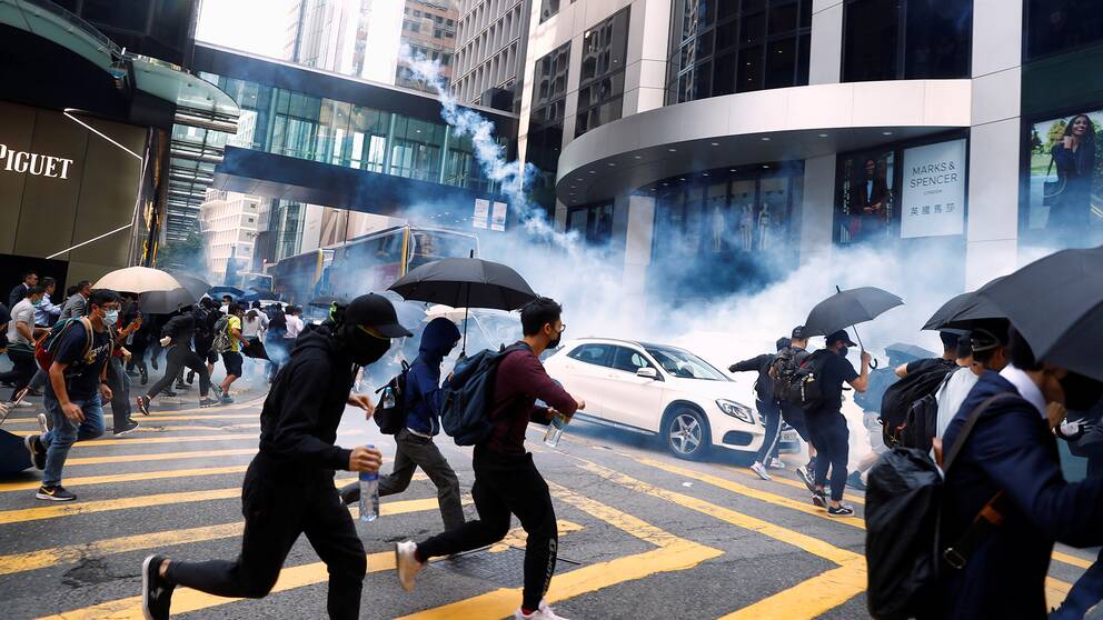 Människor springer för att skydda sig från tårgas under protester den 11 november i centrala Hongkong. 