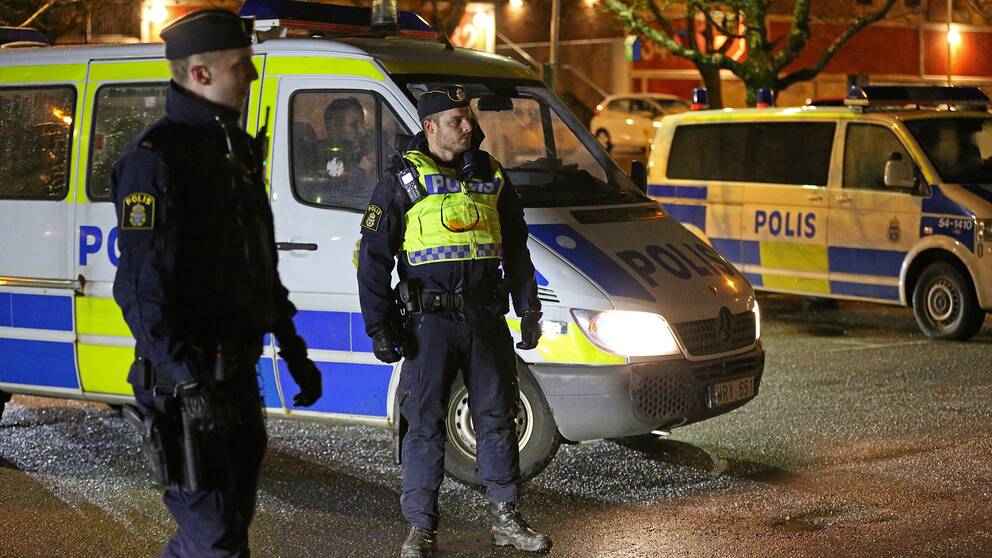 Poliser framför två polisbilar i Trollhättan
