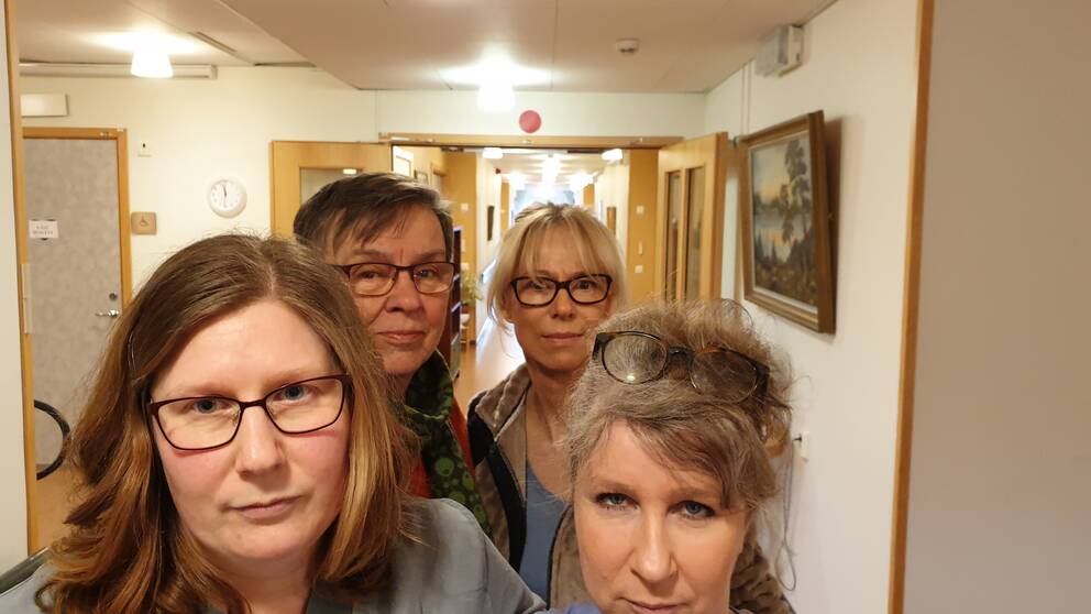 Fyra kvinnor tittar in i kameran och ser bestämda ut. De står i en korridor på ett äldreboende.