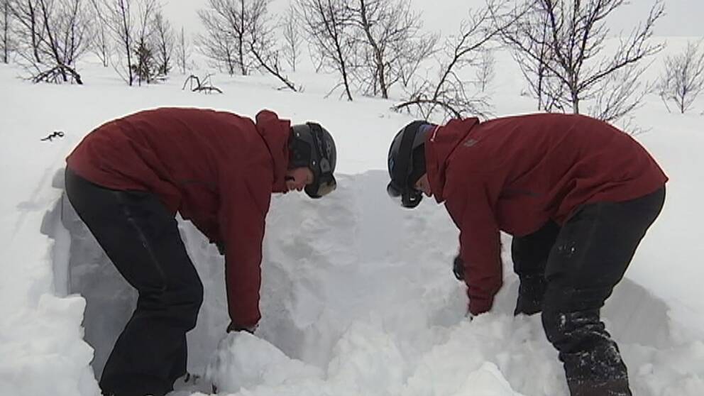 Två personer står och gräver i en snödriva