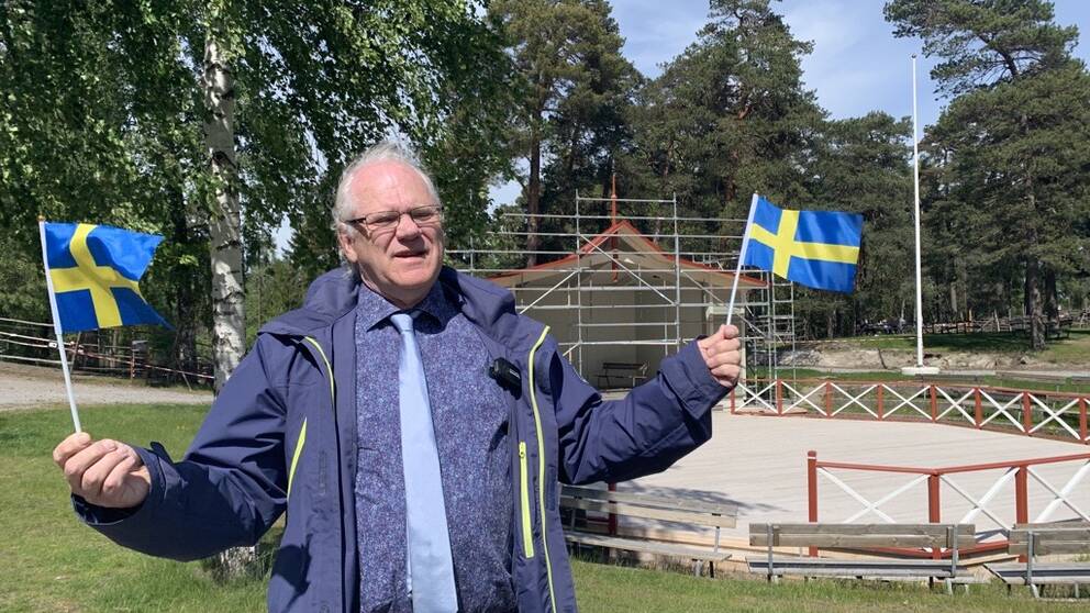 Peter Friström, ordförande i kommunfullmäktige (S) står framför scenen på Torekällberget och viftar med Sverige-flaggor 