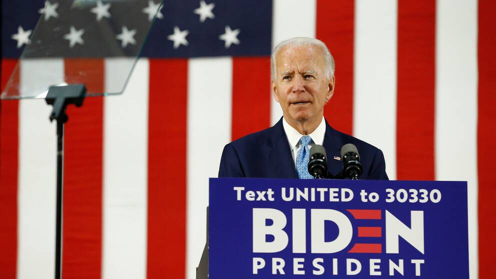 Amerikanske presidentkandidaten Joe Biden håller tal bakom podie med text där man uppmanas smsa ett nummer för att rösta fram Biden som president. Han står framför en stor amerikansk flagga.