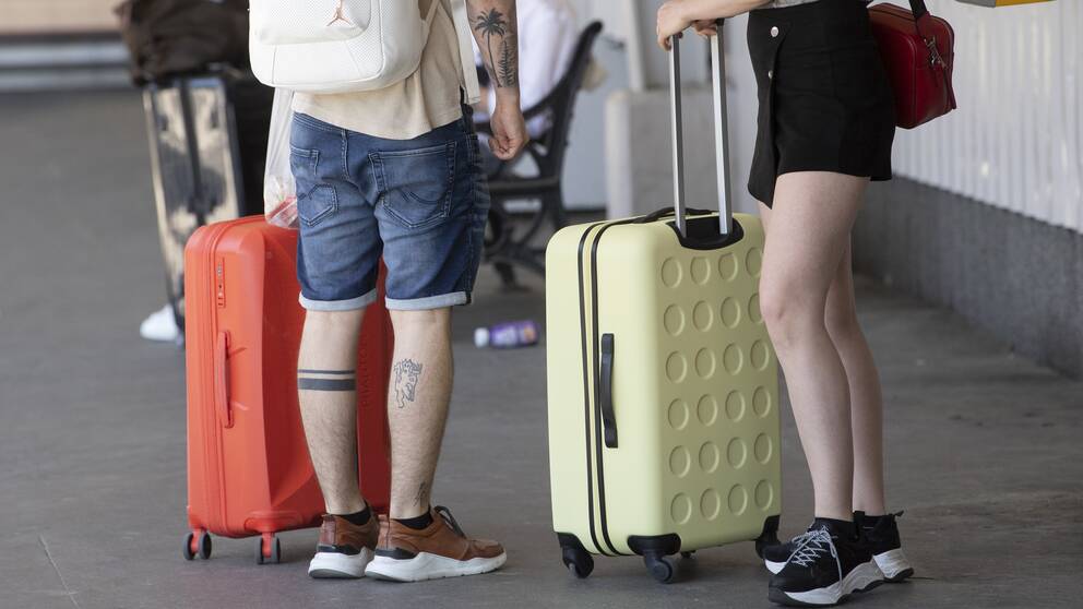 Personer med resväskor på en perrong.