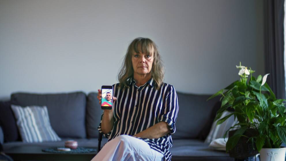 Lena håller upp en mobil med bild på den man hon trodde sig lärt känna på nätet.