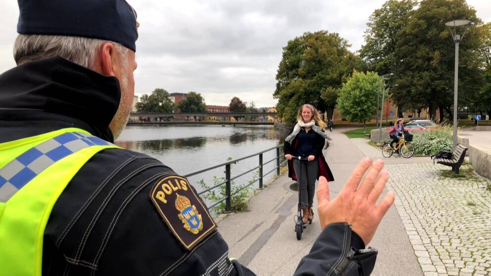 Reportern Otilia Bogen håller i en elsparkcykel och trafikpolisen Tomas Bonn inspekterar den. I bakgrunden syns Eskilstunaån och delar av Gamla stan/Söder.