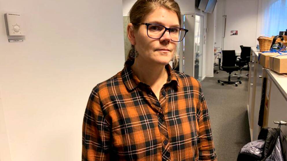 en kvinna med rutig skjorta och brunt hår och glasögon poserar i TV-huset i Falun.