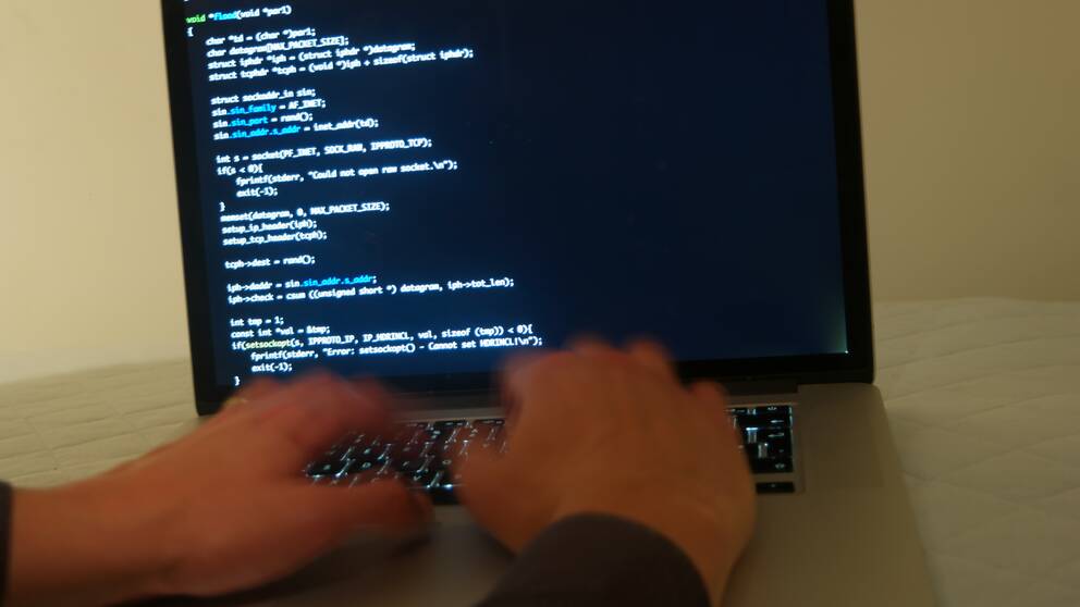 Bild på person som skriver skadlig kod på en dator.