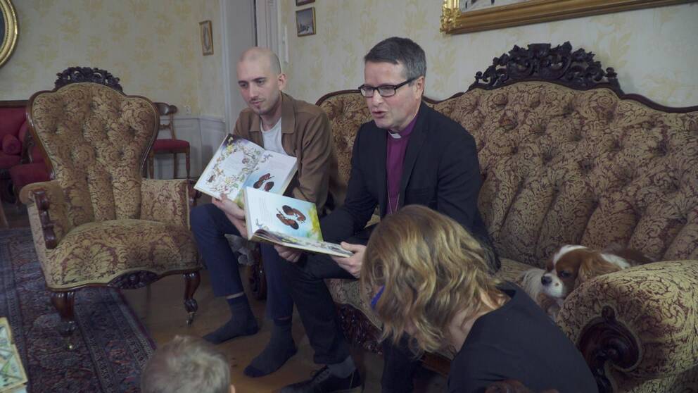 Illustratören Marcus-Gunnar Pettersson och författaren, biskop Sören Dalevi, läser ur den nya barnbibeln sittande i en soffa.