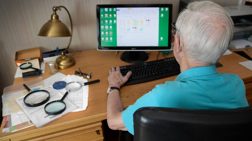 Pensionär sitter vid stationär dator.