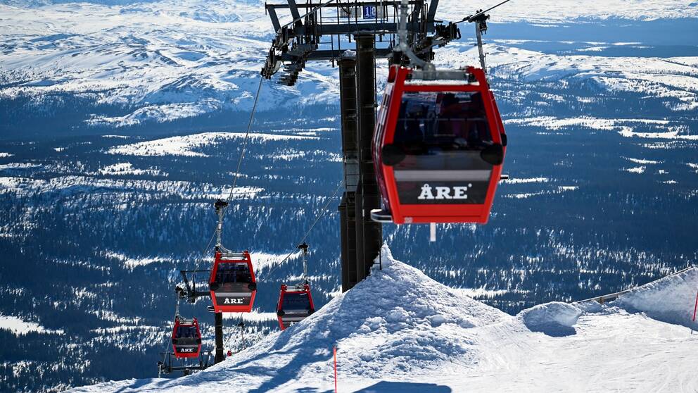 Arkivbild över en skidlift i Åre med röda kabiner med texten Åre. Snö.