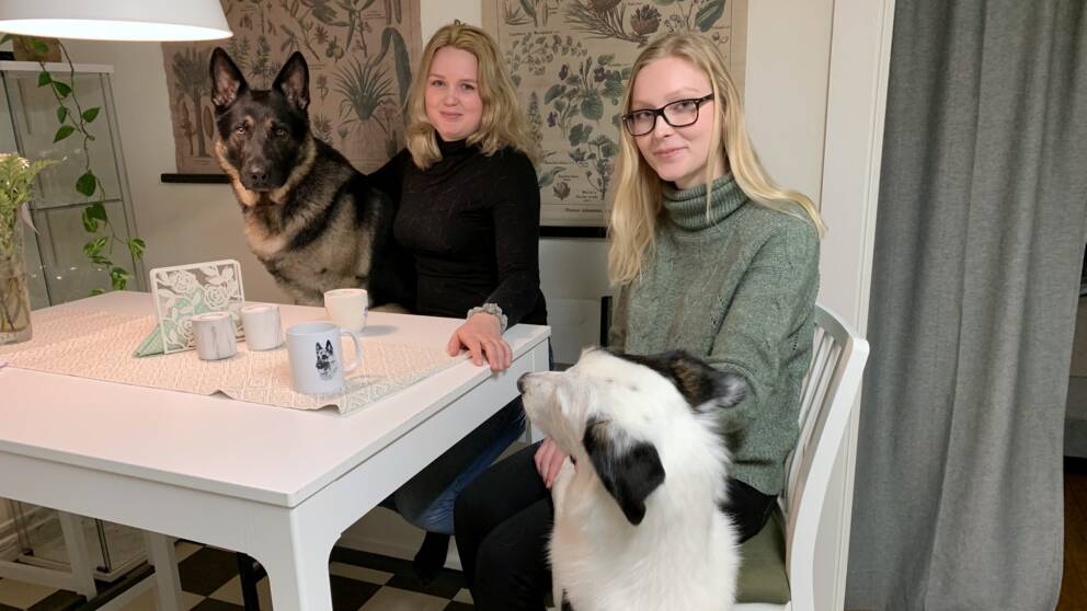 Anna och Julia med sina två hundar vid köksbordet.