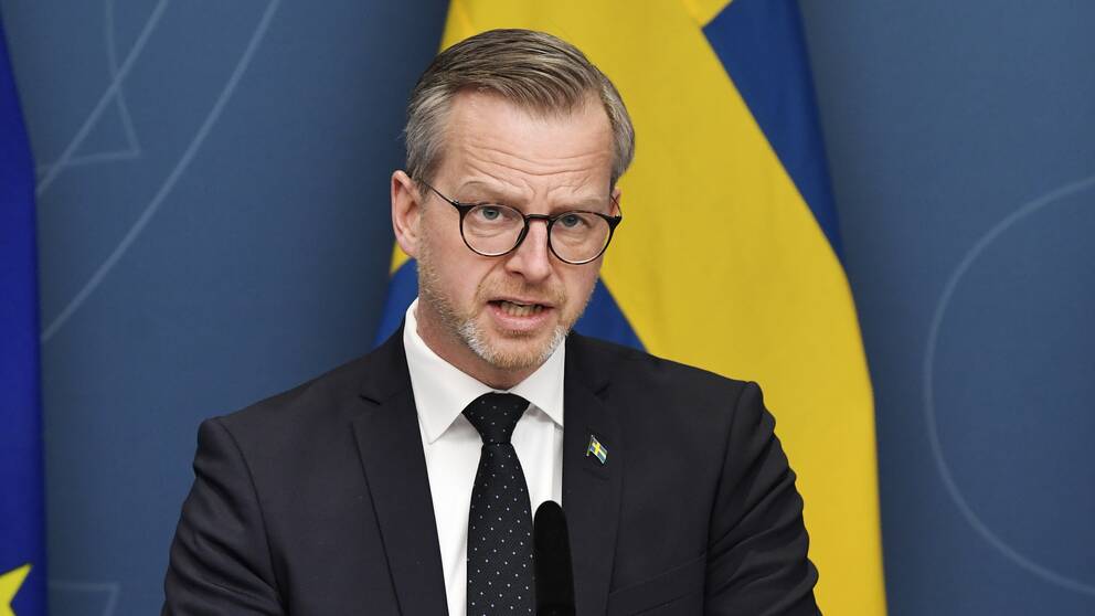Bilden visar Inrikesminister Mikael Damberg (S) under en av regeringens presskonferenser. I bakgrunden syns svenska flaggan.