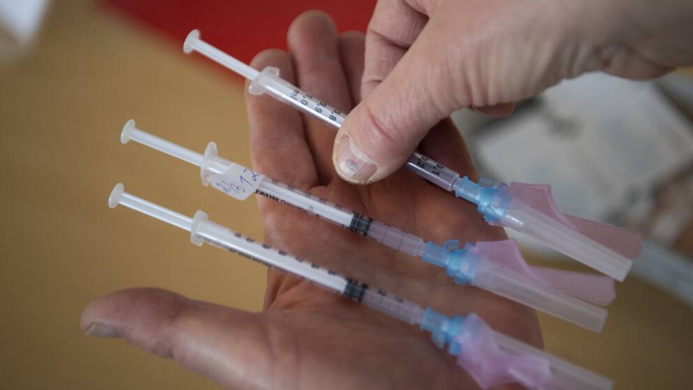 tre vaccinationssprutor som hålls i handen
