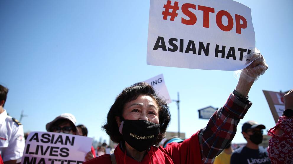 En demonstrant i Koreatown i Los Angeles håller upp en skylt där det står Stop Asian hate