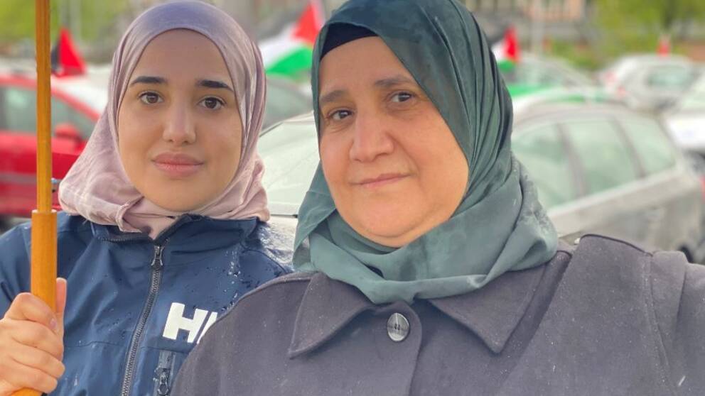 Två kvinnor iklädda färgglada hijab tittar in i kameran.