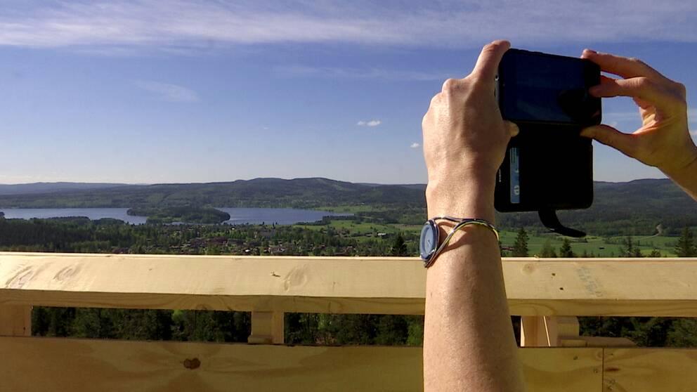 Händer som håller upp en kamera vid ett utsiktstorn i Siljansnäs