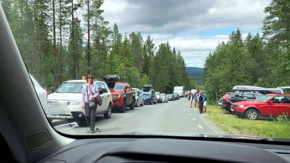 Bilar står parkerade på ena sida vägen och bara ett körfält är öppet på vägen upp mot Fulufjället. Människor går på vägen.
