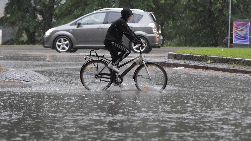 En cyklist som försöker cykla i en stor mängd vatten och regn.