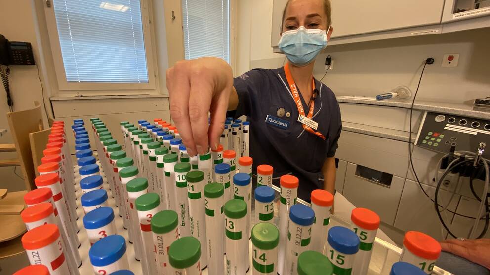 Sjuksköterskan Li Nyman snurrar på några rör i ett ställ där doftproverna förvaras.
