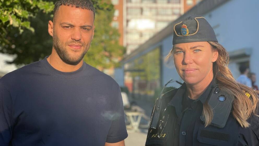 En man och en poliskvinna med höghus i bakgrunden.