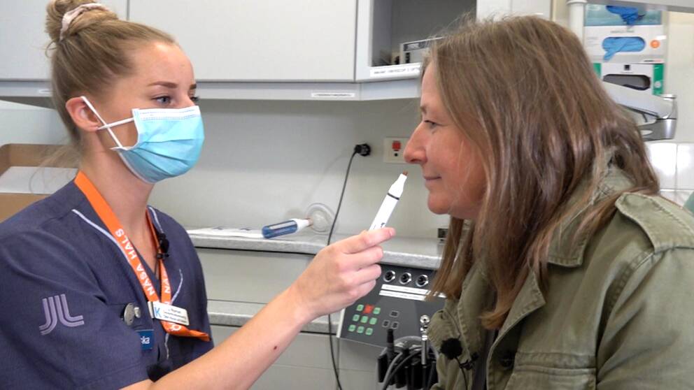 Sjuksköterskan håller fram ett rör som reportern doftar på. Inuti röret finns ett luktprov som försökspersonen ska försöka känna igen.