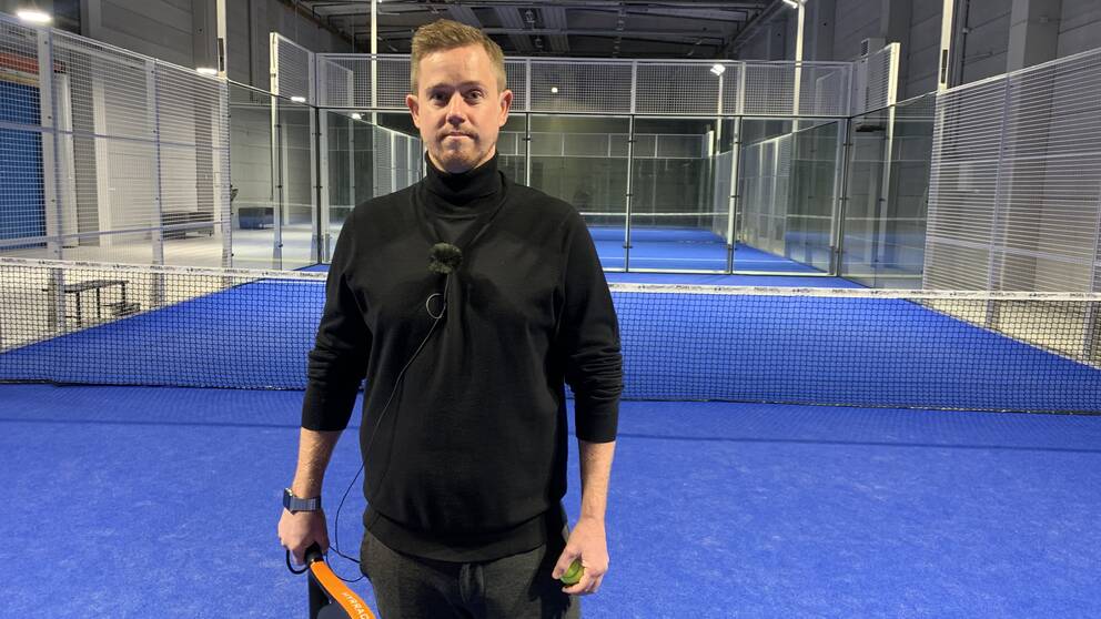 Man med padelrack på en blå padelbana.