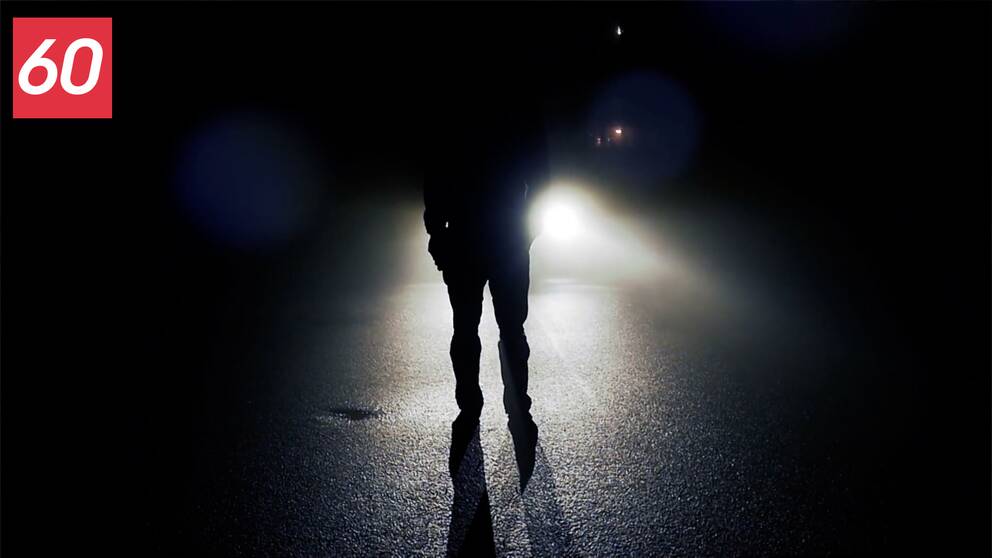 En person står framför strålkastare på en väg.