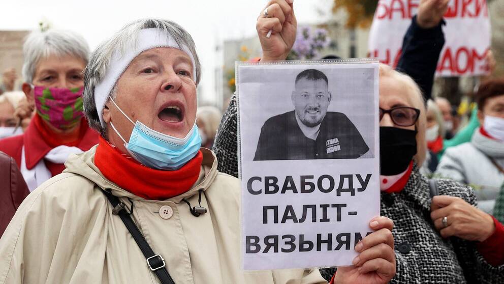 En kvinna håller upp en bild på Sergej Tichanovskij under protesterna i Belarus.