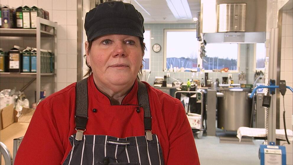 Kvinna står i ett storkök, hon har på sig arbetskläder