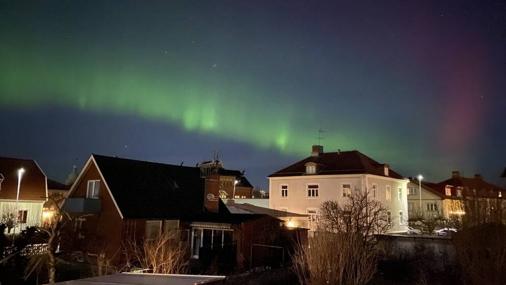 Norrsken över Skara, natten till lördagen den 15 januari 2022. Grönt skimmer syns på blå natthimmel ovanför hus i ett villakvarter.