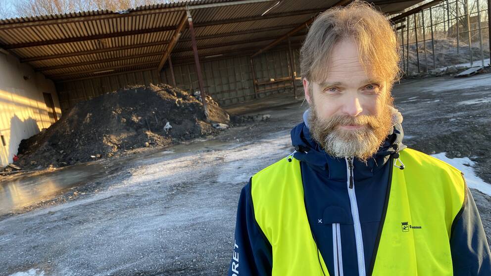 David Aronsson i varselväst står framför en stor gråsvart hög med nedmalda batterier.