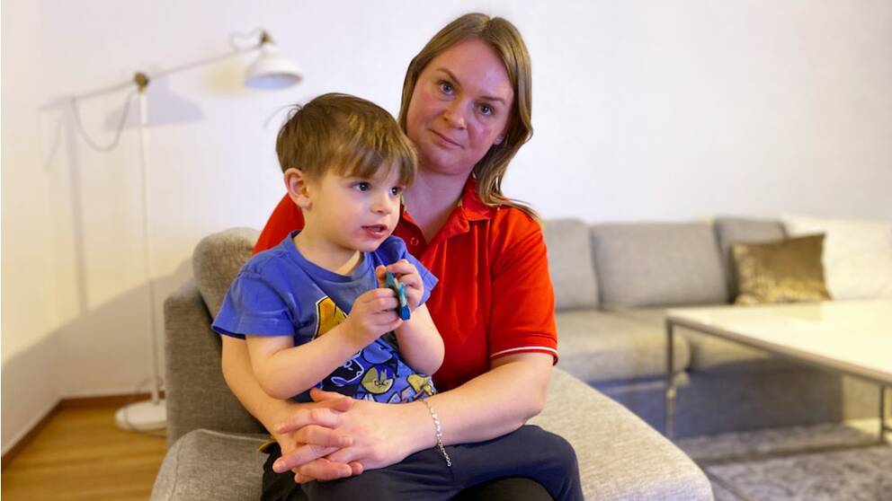 En kvinna sitter i en soffa med ett barn i knäet.