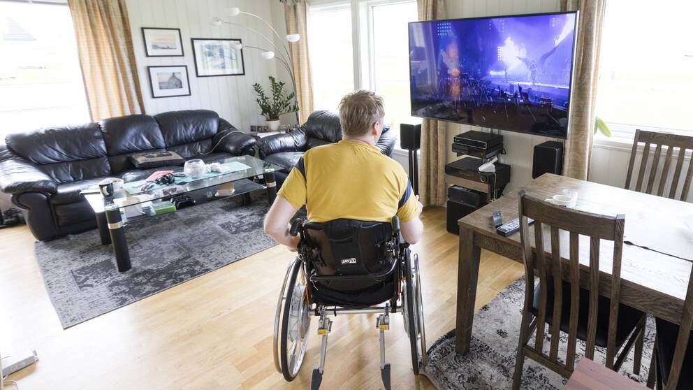 En person sitter i rullstol och kollar på tv.