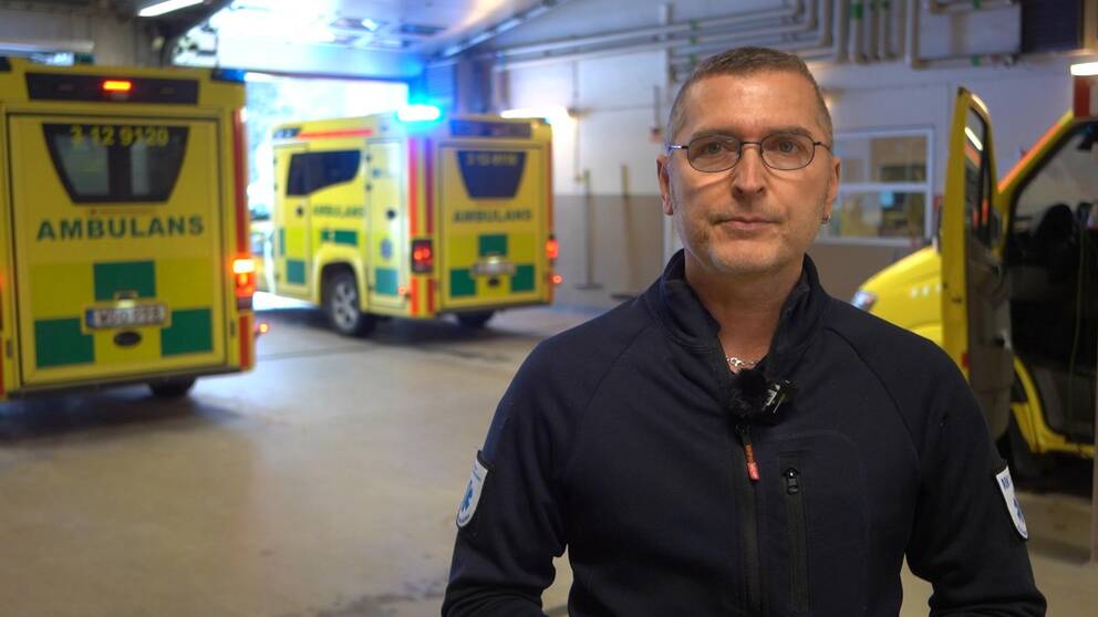 en man som står i ett garage framför tre ambulanser
